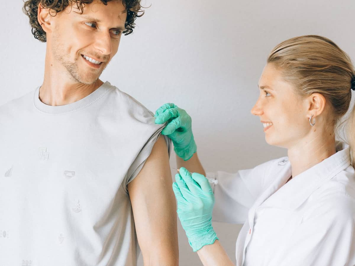Pharmacist preparing to give a patient a vaccine in his upper arm
